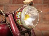 a close up of a red motorcycle with a brick wall in the background