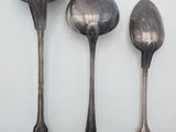three spoons and a spoon rest on a white surface