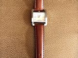 an image of a watch sitting on top of a brown leather bag