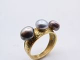 a close up of a ring with three pearls on it