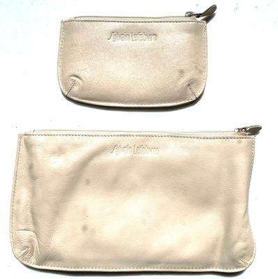 pair of white leather purses with zippers sitting on a white surface