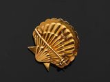 an image of a gold shell broochle on a black surface