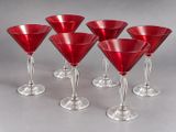 six red wine glasses lined up in a row on a gray surface