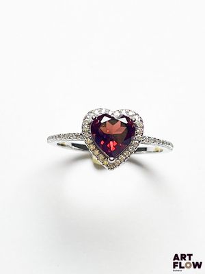 un gros plan d'une bague en forme de cœur sertie de diamants, sur fond blanc