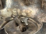 a silver plate with a cow on it on a table