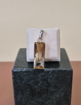 un petit pendentif en verre posé sur un bloc de marbre, sur une table