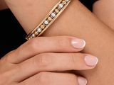 Gros plan sur les mains d'une femme portant un bracelet en or et un bracelet de perles