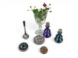 un vase en verre contenant des fleurs, à côté d'autres objets en verre