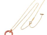 a close up of a gold necklace with a red circle on it
