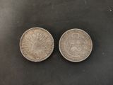 two silver coins on a black surface