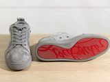 grey sneakers with red soles sitting on top of a wooden table