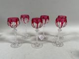 six verres à vin rouge ornés de motifs en spirale, posés sur une table