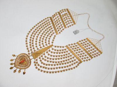 une image représentant un collier en or orné d'une pierre rouge au centre