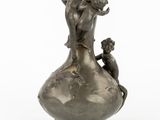 a silver vase with a statue of a woman and a child on it