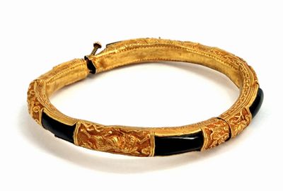 an image of a gold and black bracelet on a white surface