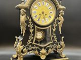 une horloge noire et dorée surmontée d'un oiseau