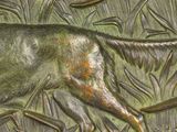 a bronze plaque of a dog running in the grass