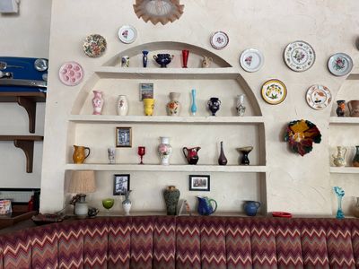 de nombreuses assiettes et vases accrochés au mur au-dessus d'un canapé