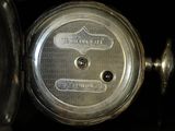 a close up of a person ' s hand holding a silver pocket watch