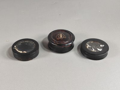 trois petits récipients noirs et blancs posés sur une table