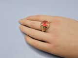 an image of a woman ' s hand holding a ring with a red stone