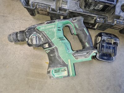 une perceuse filaire et deux batteries posées par terre