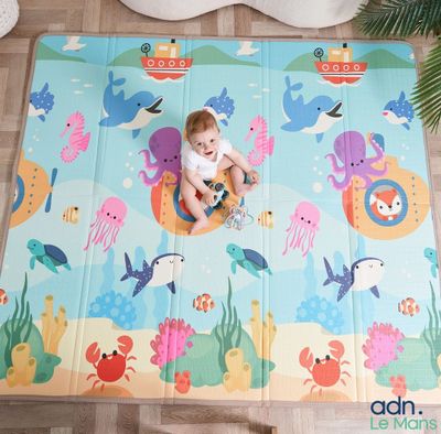 un bébé assis sur un tapis posé à même le sol