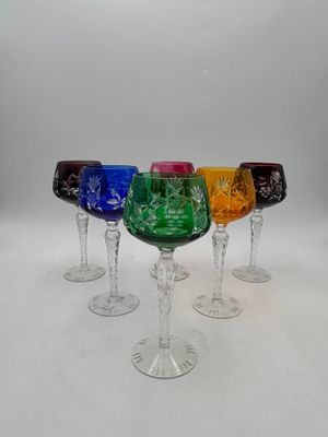six wine glasses with different colored designs are lined up in a row