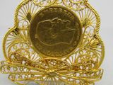 une image représentant une broche en or avec une pièce de monnaie au centre