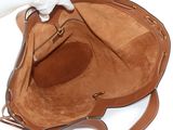 someone holding a brown purse with a white glove on top of it