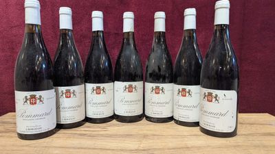 six bottles of wine are lined up on a wooden table