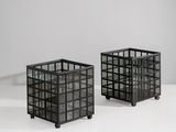 une paire de jardinières cubiques en verre noir, posées sur des roulettes, sur une surface blanche