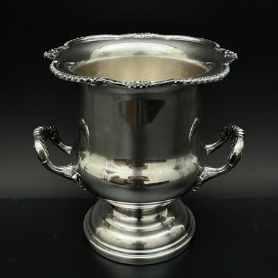 un vase en argent muni d'une anse, posé sur une table noire