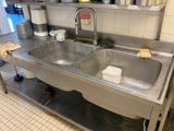 un évier en acier inoxydable dans une cuisine professionnelle, avec des casseroles et des poêles posées sur le plan de travail