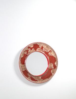une assiette rouge ornée d'un motif circulaire sur un fond blanc