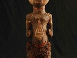 une statue en bois représentant un homme à la tête et aux jambes disproportionnées