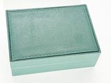 une boîte verte posée sur une surface blanche