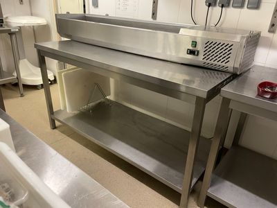 une grande table de travail en acier inoxydable dans une cuisine professionnelle