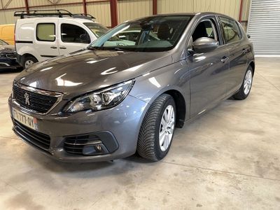 La voiture grise est garée dans un garage, avec d'autres voitures en arrière-plan.
