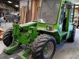 a green tractor that is parked in a warehouse