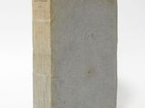 an old book sitting on top of a white table next to a white wall