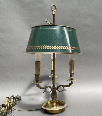 an antique brass table lamp with a green shade and two candles