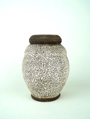 un vase blanc avec un couvercle marron posé sur une table