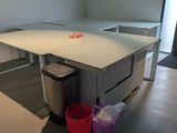 a desk with a trash can and a trash can in the corner