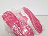 pink slippers are wrapped in plastic on top of a white surface