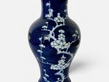 un vase bleu orné de fleurs blanches sur fond blanc