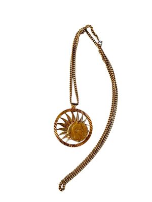 un gros plan sur un collier en or orné d'un soleil