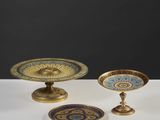 trois objets en laiton et en verre posés sur une table blanche