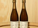 deux bouteilles de vin posées sur un tonneau en bois