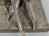 bronze statue of a person with a sword and a pot